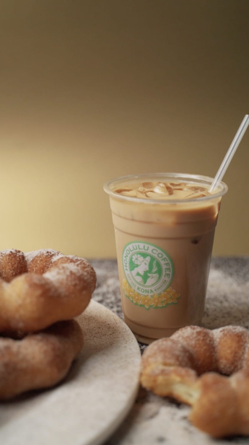 Iced coffee in Honolulu Coffee cup with sugar-dusted donuts