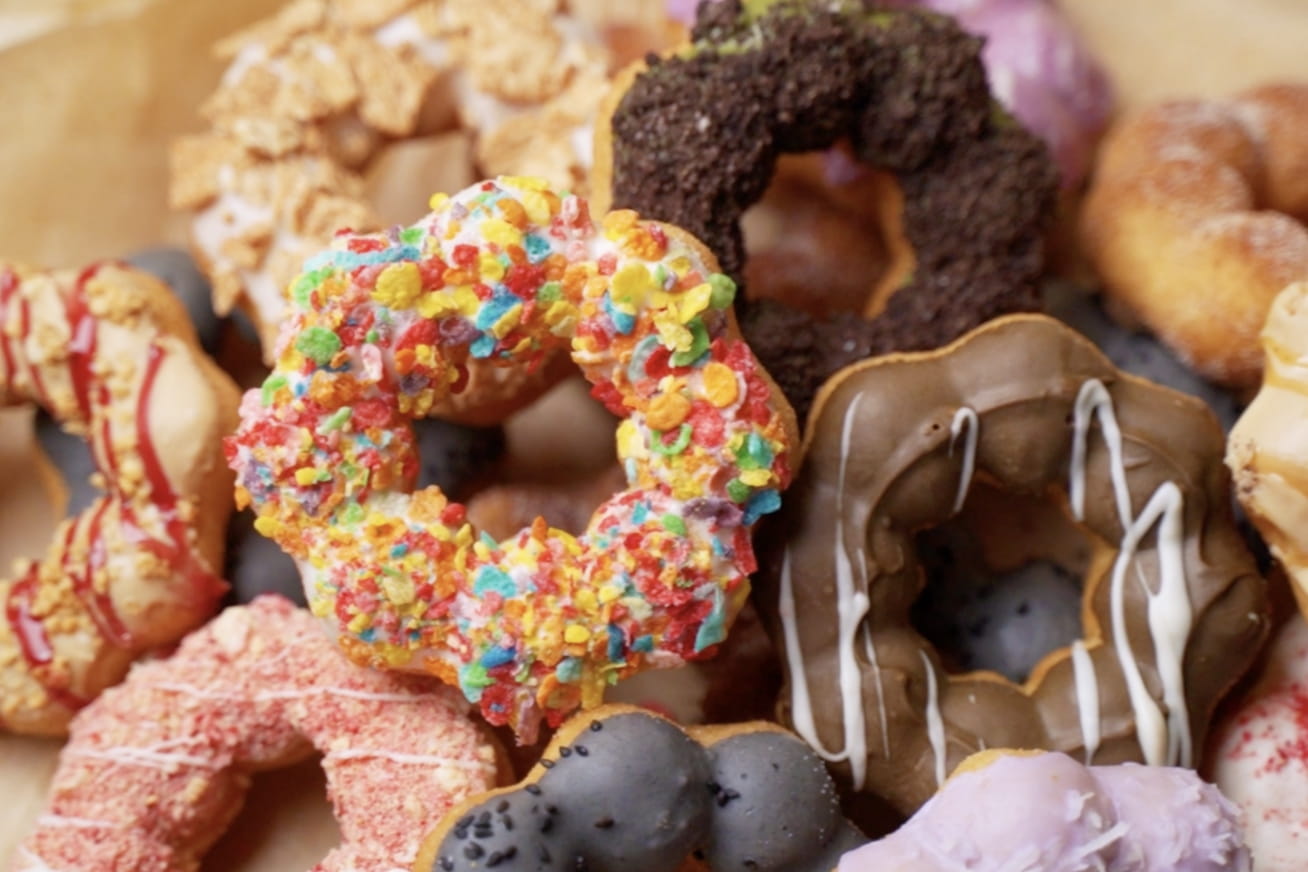 Seven star-shaped mochi donuts with various toppings and glazes